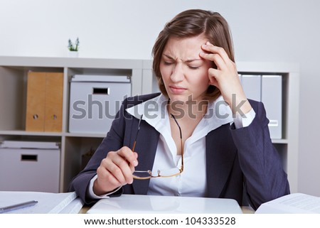Business woman sitting with headache at her desk in the office