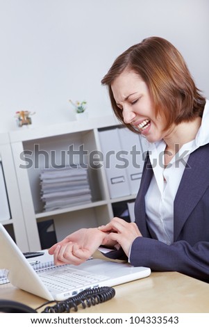 Woman with computer in office with arthritis in her hand wrist