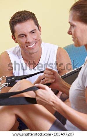 Happy fitness trainer talking to woman in fitness center