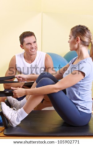 Attractive woman exercising in fitness center and talking to male fitness trainer