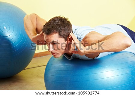 Man exercising his back on gym ball in fitness center