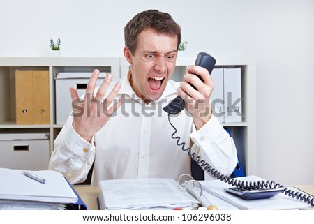 Angry business man screaming at phone in his office