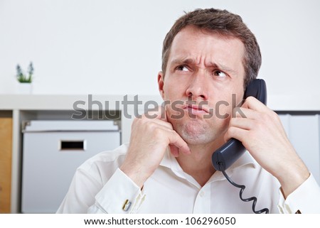 Frustrated business man on the phone in waiting queue