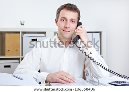 Smiling business man receiving a phone call in the office