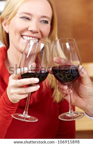 Elderly happy woman raises her glass of red wine for a toast