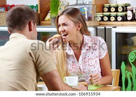 Man in cafÃ?Â© giving woman a bite of his muffin