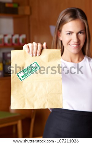 Young attractive woman holding paper bag in health food store