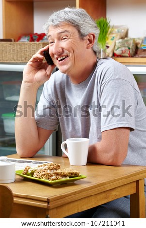 Smiling senior man making a call with his smartphone in a cafÃ?Â©