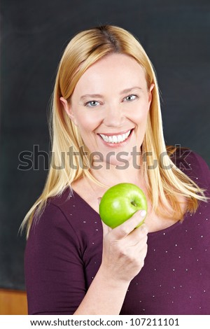 Smiling female teacher holding a green apple