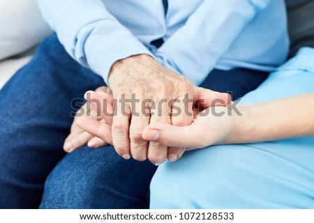 Caring nurse or geriatric nurse holds hand of an old woman
