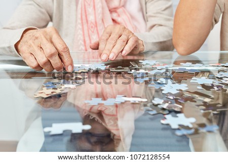Hands of seniors playing puzzle on the table as a memory training