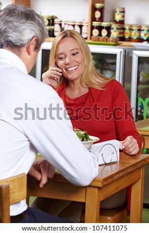 Elderly woman using her smartphone in a restaurant to make a call