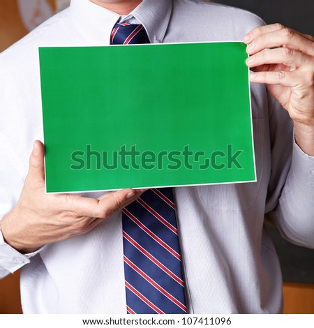 Manager holding empty green sign in front of his chest