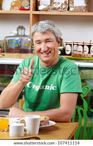 Elderly happy man in organic cafÃ?Â© holding his thumbs up