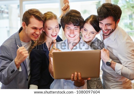 Start-up team with laptop celebrating their success