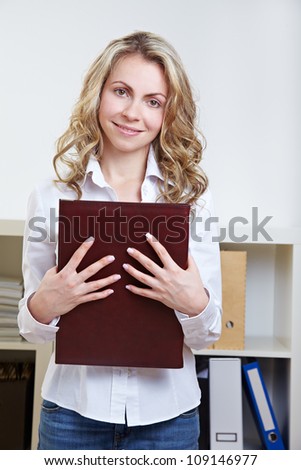 Happy blonde woman standing with application portfolio in the office