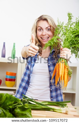 Young happy woman with vegetables in kitchen holding her thumbs up