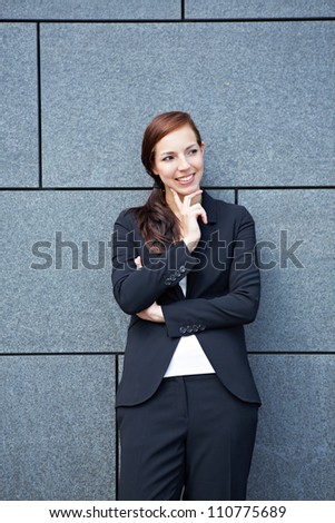 Attractive pensive business woman leaning on wall