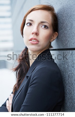 Attractive urban business woman leaning on a wall