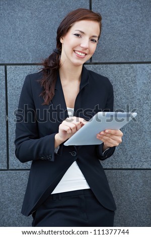 Business woman with digital tablet computer leaning on wall