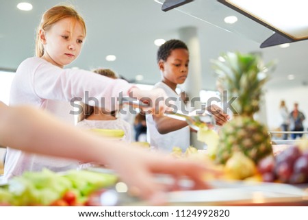 Students in elementary school take fruit at the buffet in the cafeteria