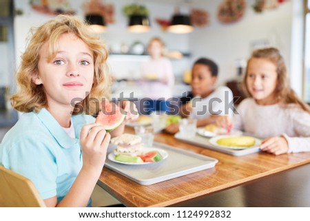 Happy boy and his friends eat in the canteen of the elementary school