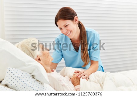 Caring geriatric nurse cares for ill senior citizen in nursing home or hospice