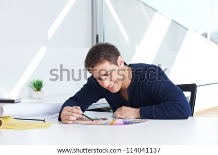 Graphic designer sitting with color fans and pencil in his office