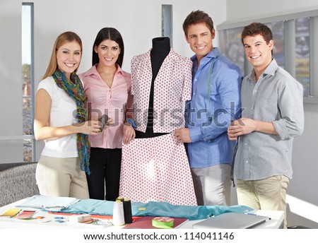 Happy Fashion design team in a studio around a dress form