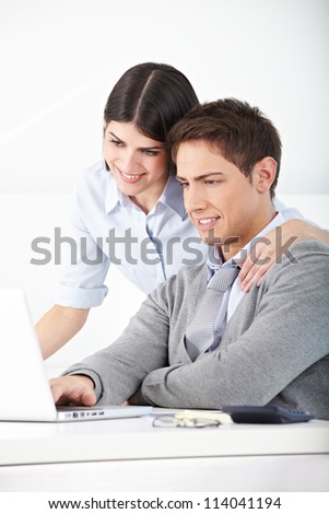 Man and woman in an office looking at laptop computer