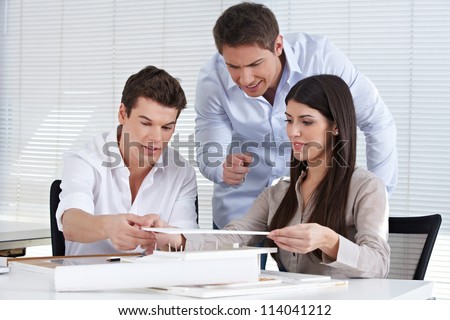 Three architects in an office creating a house model together