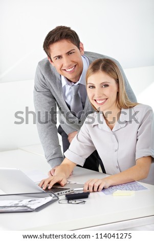 Happy man and woman working together with laptop computer in an office