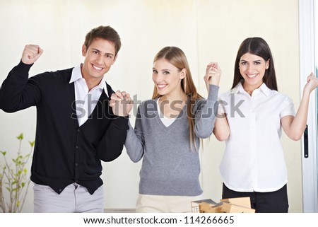 Three happy students holding their hands and cheering in university