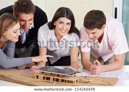 Four architects discussing a 3D house draft in their office