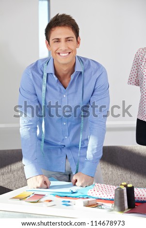 Portrait of happy fashion designer standing in his office