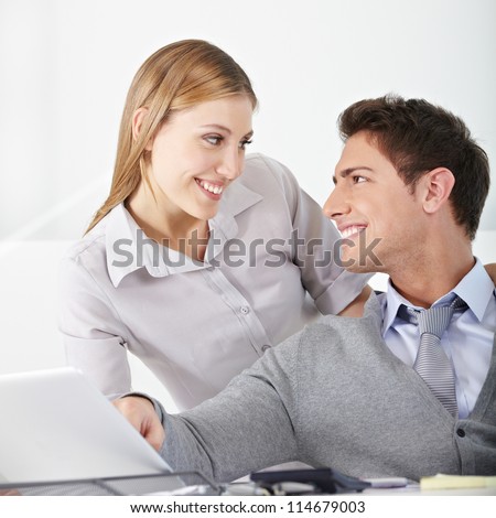 Smiling young business woman flirting with a man in the office