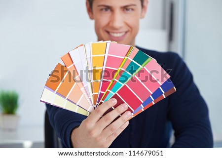 Happy graphic designer holding color fan in his hand