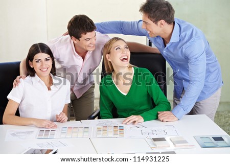 Two happy couples deciding house building materials on a desk