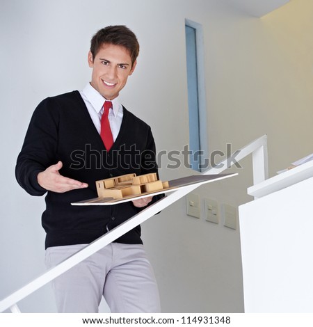 Happy Architect presenting house model on stairway