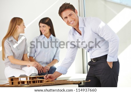 Happy architect in office working on a house model
