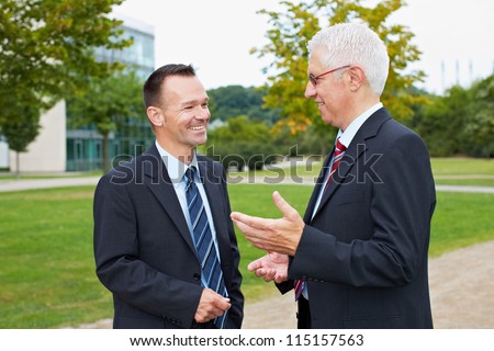Two happy business people talking with each other in a park