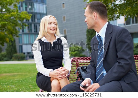 Two business people talking outside on a park bench