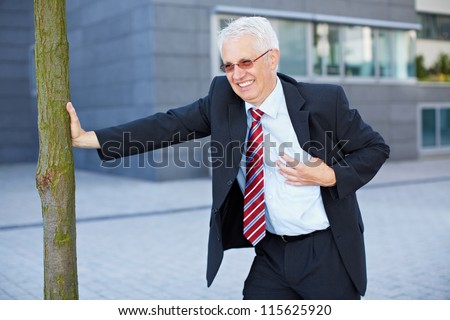 Business man getting a heart attack and holding hand to his chest