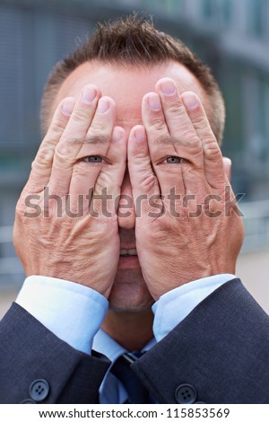 Business man with eyes on his hands over his face