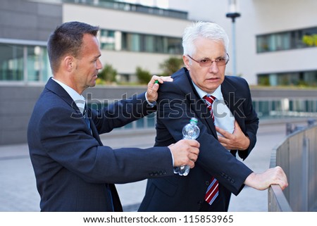 Business man helping senior with heart attack with a bottle of water