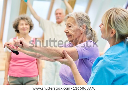 Senior woman in physiotherapy is doing exercise with elastic band with the help of trainer