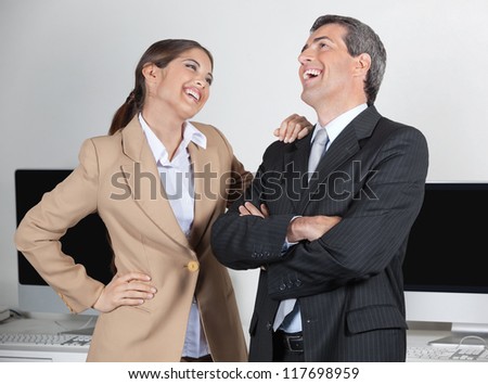 Happy manager and secretary laughing about a joke in the office