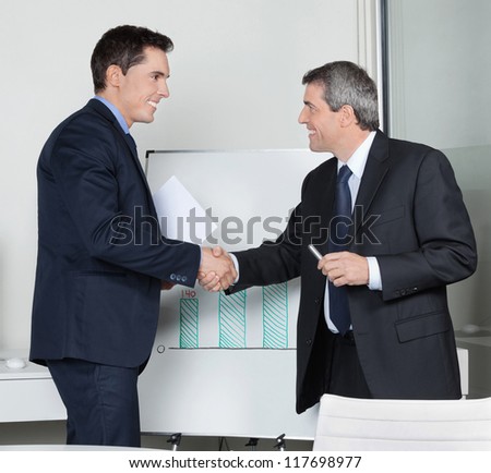 Two happy successful business partner shaking hands in the office