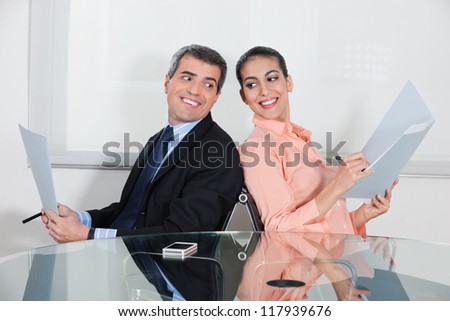 Businessman and woman spying in each others files in the office