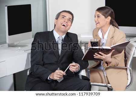 Happy business man and secretary laughing together in the office